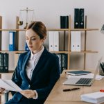 female lawyer in suit with documents in hands at workplace in office